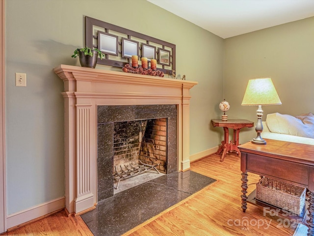 living area featuring baseboards, wood finished floors, and a tile fireplace