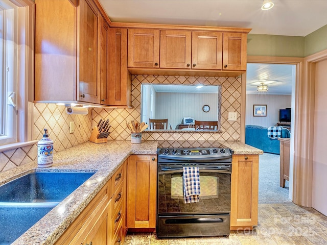 kitchen featuring light stone countertops, tasteful backsplash, black / electric stove, and brown cabinets