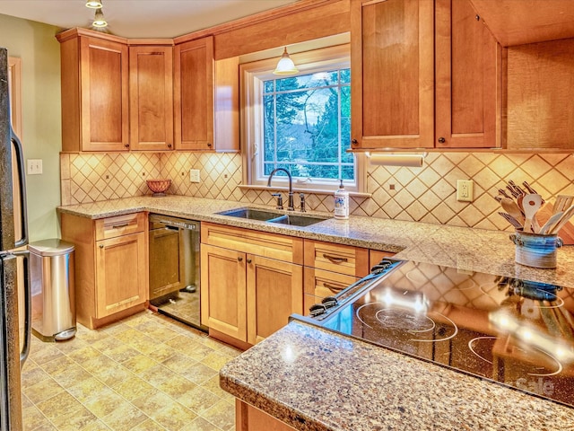 kitchen with a sink, freestanding refrigerator, light stone countertops, dishwasher, and tasteful backsplash