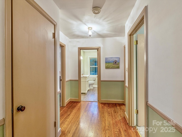 corridor featuring light wood-type flooring and baseboards