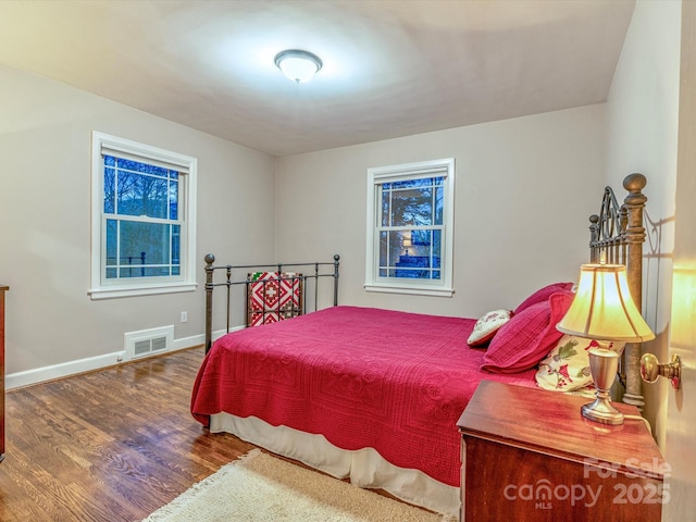 bedroom with wood finished floors, visible vents, and baseboards