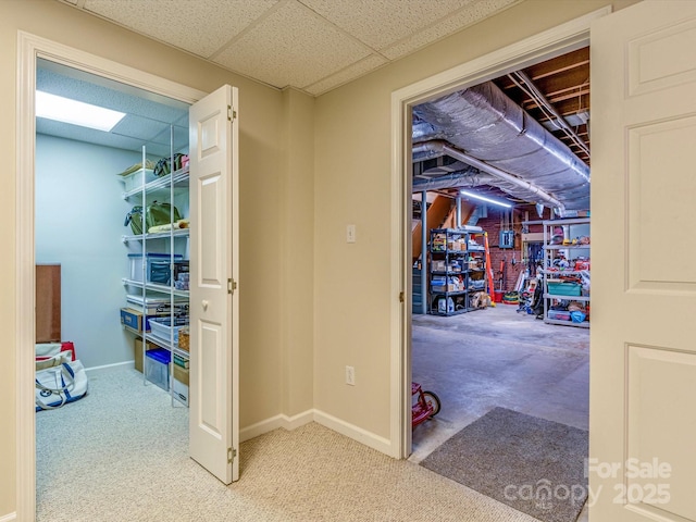 hall featuring a paneled ceiling, carpet, and baseboards