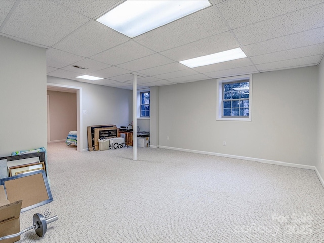 finished below grade area with carpet floors, a drop ceiling, visible vents, and baseboards