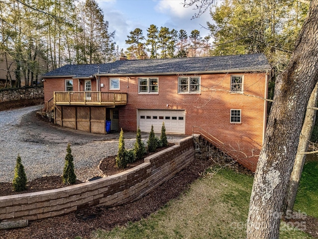 exterior space featuring a deck, brick siding, a chimney, and an attached garage