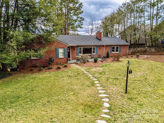 ranch-style house with brick siding, a chimney, a front yard, and a shingled roof