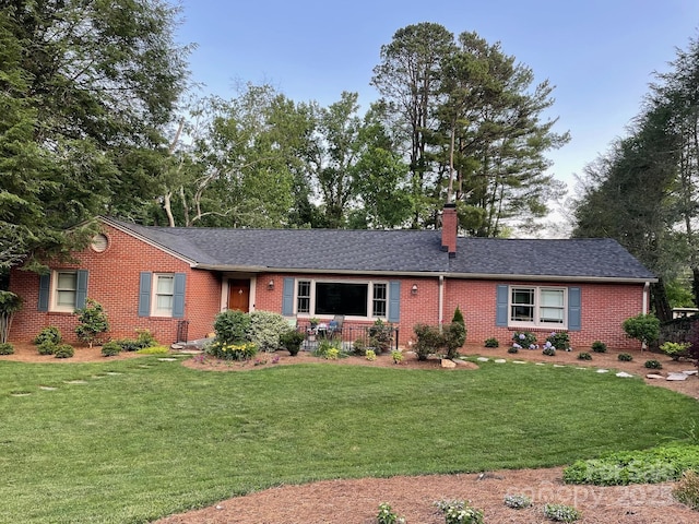 single story home featuring brick siding, a chimney, and a front lawn