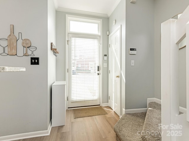 doorway to outside featuring light wood-style flooring, baseboards, and crown molding