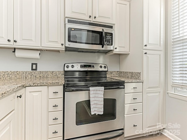 kitchen with appliances with stainless steel finishes, light stone countertops, and white cabinets