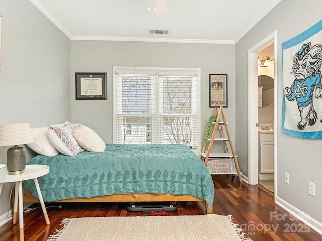 bedroom featuring baseboards, visible vents, connected bathroom, wood finished floors, and crown molding