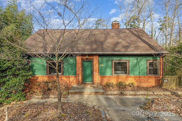 view of front of home featuring brick siding and a chimney