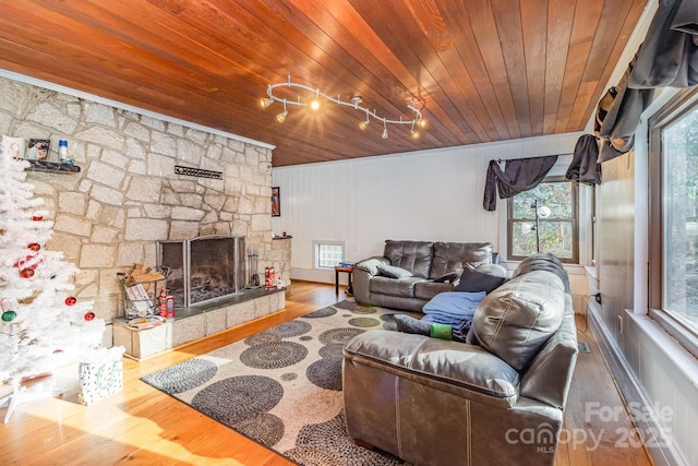 living area featuring wooden ceiling, a stone fireplace, and wood finished floors