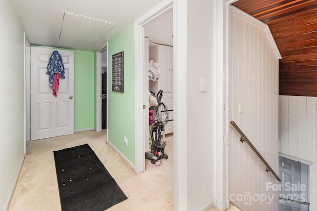 hallway featuring baseboards, an upstairs landing, attic access, and light colored carpet