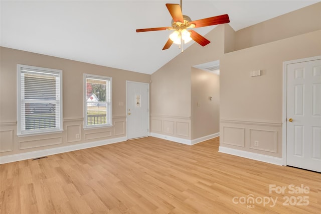 empty room featuring lofted ceiling, light wood finished floors, visible vents, and a ceiling fan