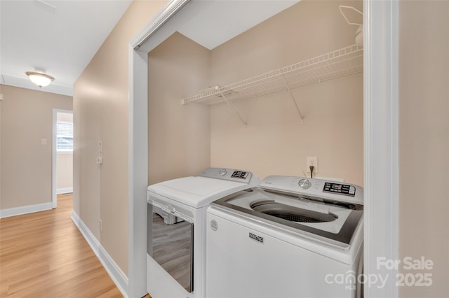 washroom featuring light wood-type flooring, baseboards, and washing machine and clothes dryer