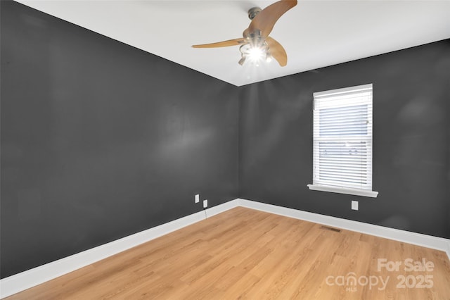 empty room with light wood-style floors, visible vents, baseboards, and a ceiling fan