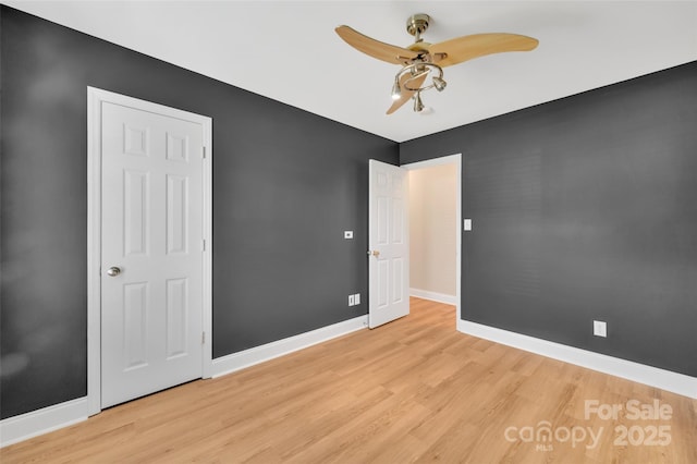 unfurnished bedroom featuring a ceiling fan, light wood-style flooring, and baseboards