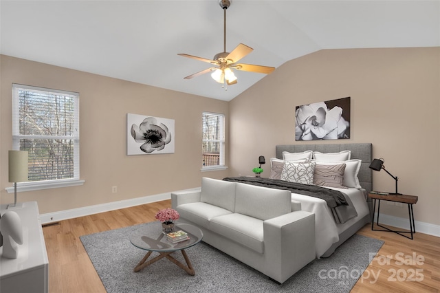 bedroom featuring multiple windows, vaulted ceiling, baseboards, and wood finished floors