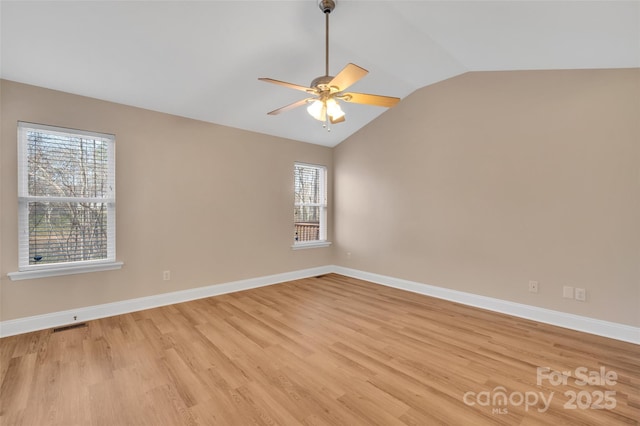 spare room featuring light wood-style flooring, visible vents, baseboards, vaulted ceiling, and a ceiling fan