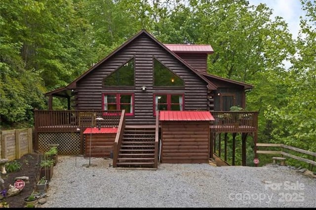 back of house with metal roof, fence, a deck, and stairs