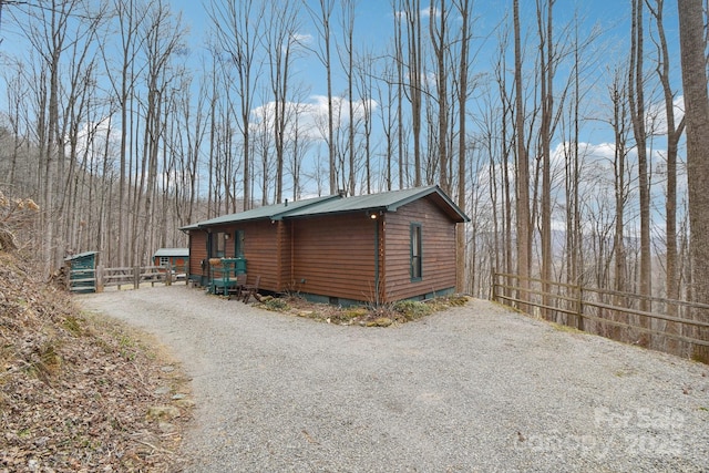 view of home's exterior with metal roof, driveway, and fence