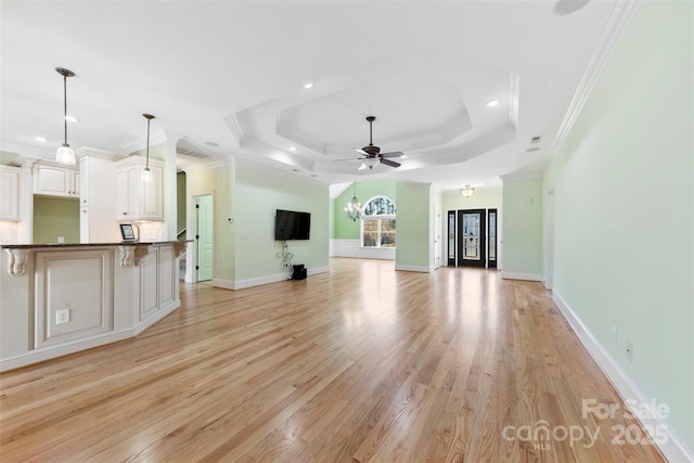 unfurnished living room with crown molding, a raised ceiling, light wood-style flooring, ceiling fan, and baseboards