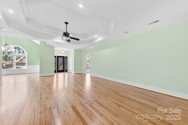 unfurnished living room featuring ornamental molding, light wood-type flooring, and a raised ceiling