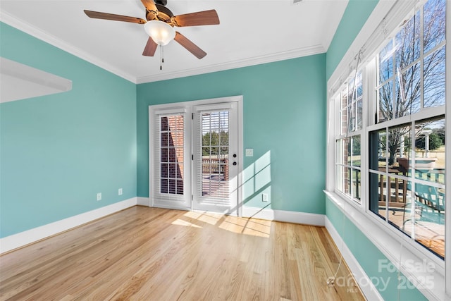 empty room featuring baseboards, wood finished floors, and crown molding