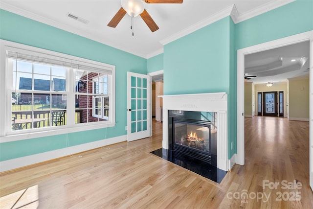 living area with wood finished floors, ornamental molding, a fireplace with flush hearth, and visible vents