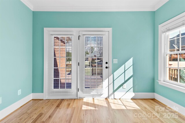 doorway featuring ornamental molding, wood finished floors, and baseboards