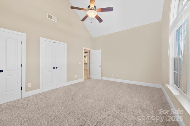 unfurnished bedroom featuring baseboards, visible vents, carpet flooring, high vaulted ceiling, and a closet