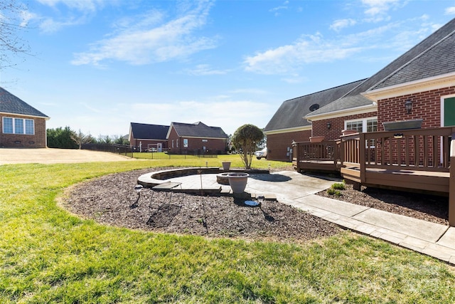 view of yard featuring an outdoor fire pit, a patio, a deck, and fence