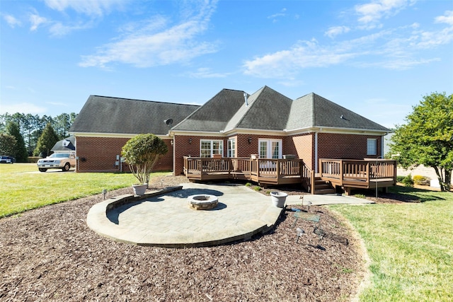 rear view of house with brick siding, a lawn, an outdoor fire pit, a patio area, and a wooden deck