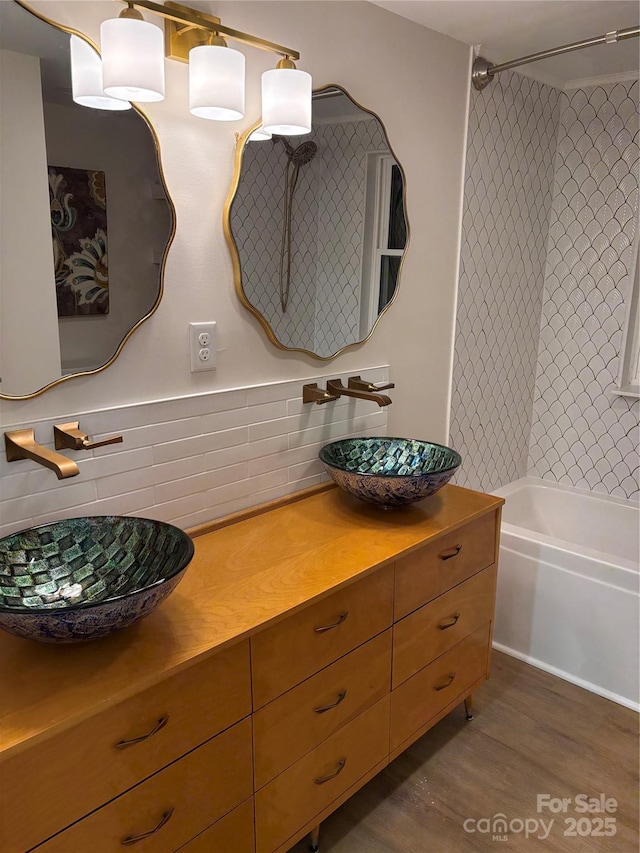 full bathroom with shower / bath combination, backsplash, a sink, and wood finished floors