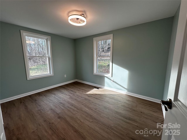 unfurnished room featuring visible vents, baseboards, and dark wood finished floors