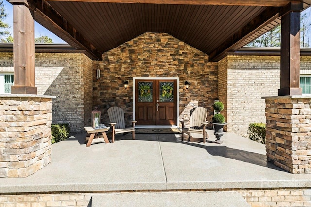 entrance to property featuring stone siding, french doors, and brick siding