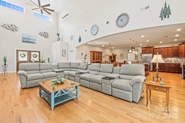 living room with a ceiling fan, arched walkways, visible vents, and light wood finished floors