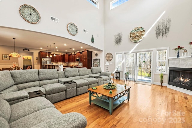 living area featuring a lit fireplace, visible vents, and light wood-style floors