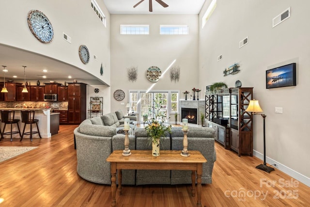 living area featuring light wood-type flooring, visible vents, and a lit fireplace