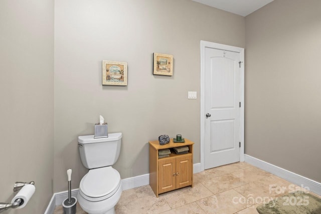 bathroom with toilet, baseboards, and tile patterned floors