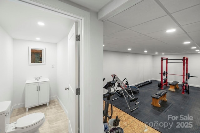 workout room with recessed lighting, a sink, a paneled ceiling, and baseboards