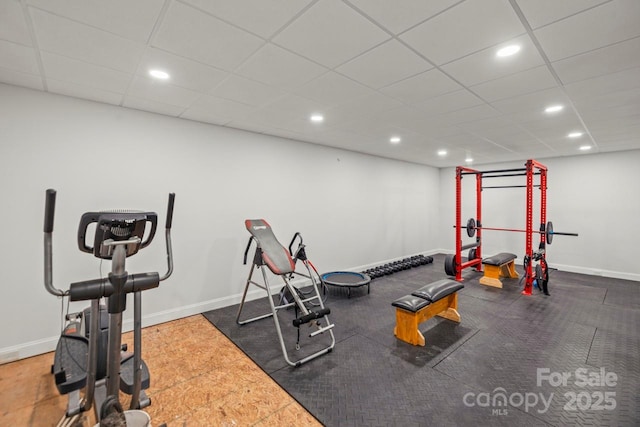 exercise area featuring a paneled ceiling, baseboards, and recessed lighting