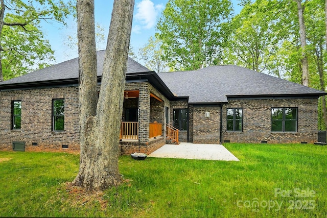 rear view of property with brick siding, a shingled roof, a yard, and crawl space