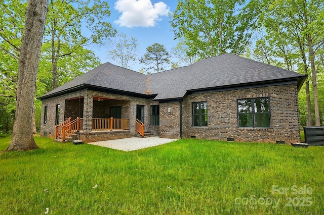 rear view of property featuring crawl space, a patio area, brick siding, a yard, and a shingled roof
