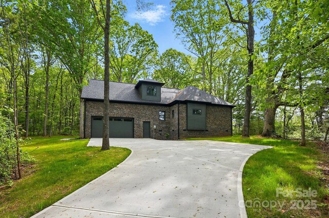view of front of property with brick siding, a front lawn, an attached garage, and driveway