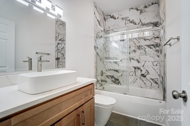 bathroom featuring toilet, enclosed tub / shower combo, tile patterned flooring, and vanity