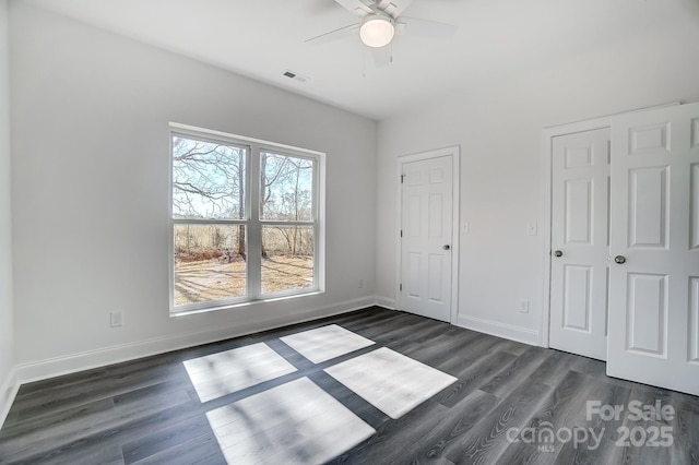 unfurnished bedroom featuring baseboards, visible vents, and dark wood-type flooring