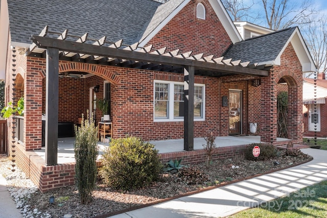 exterior space featuring a shingled roof, a patio area, brick siding, and a pergola