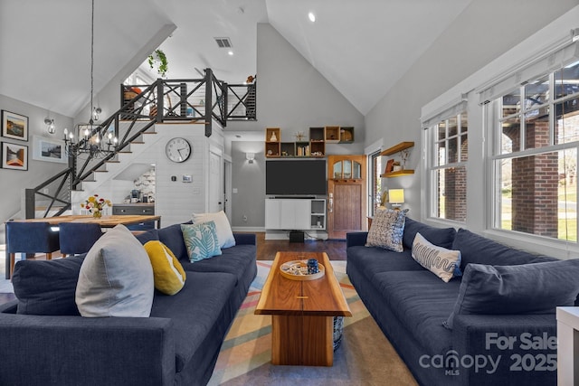 living room with visible vents, wood finished floors, high vaulted ceiling, baseboards, and stairs