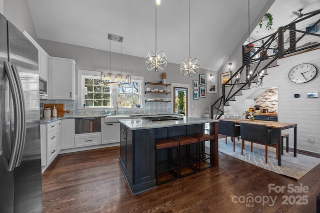 kitchen with dark wood-type flooring, light stone counters, stainless steel appliances, and a warming drawer