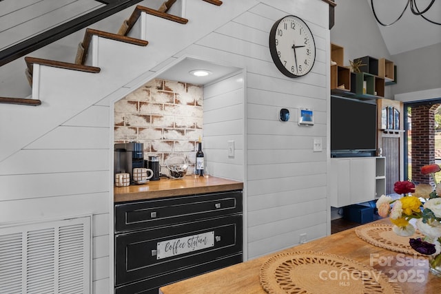 bar with lofted ceiling, wooden walls, and visible vents